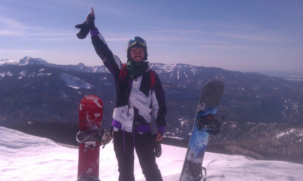 JJ Nader at a snowy mountain summit with snowboards